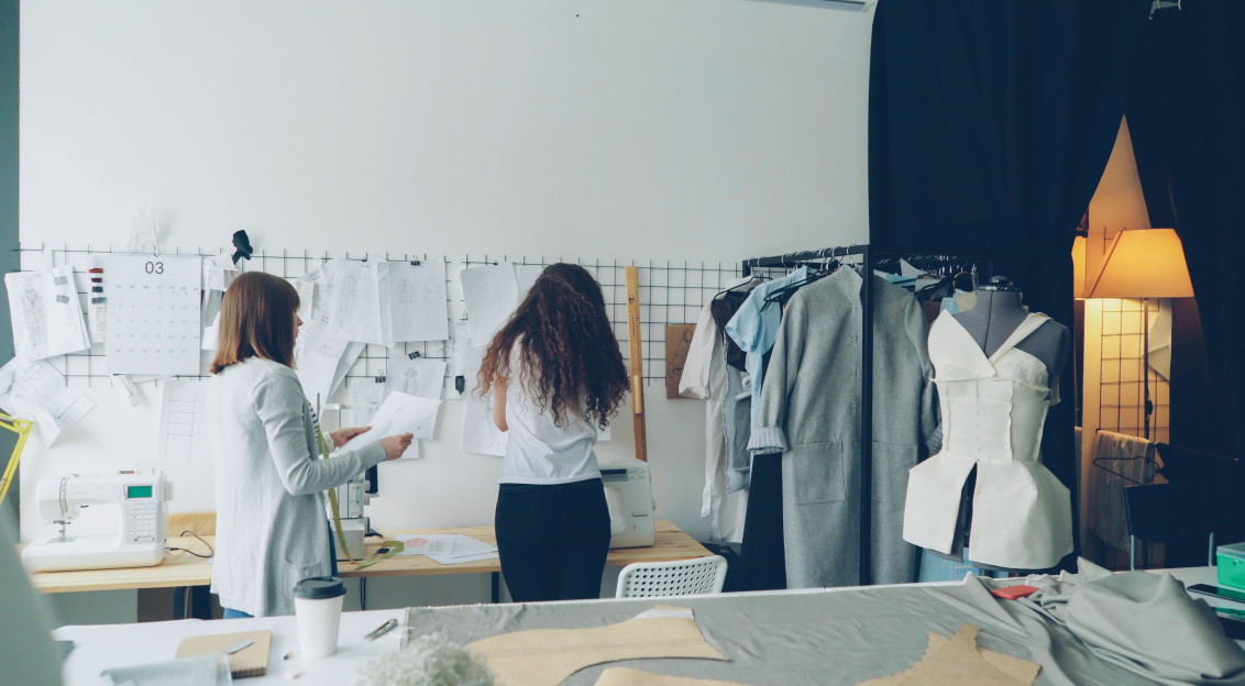 Fashion designers working on clothing sketches and patterns in a modern studio.