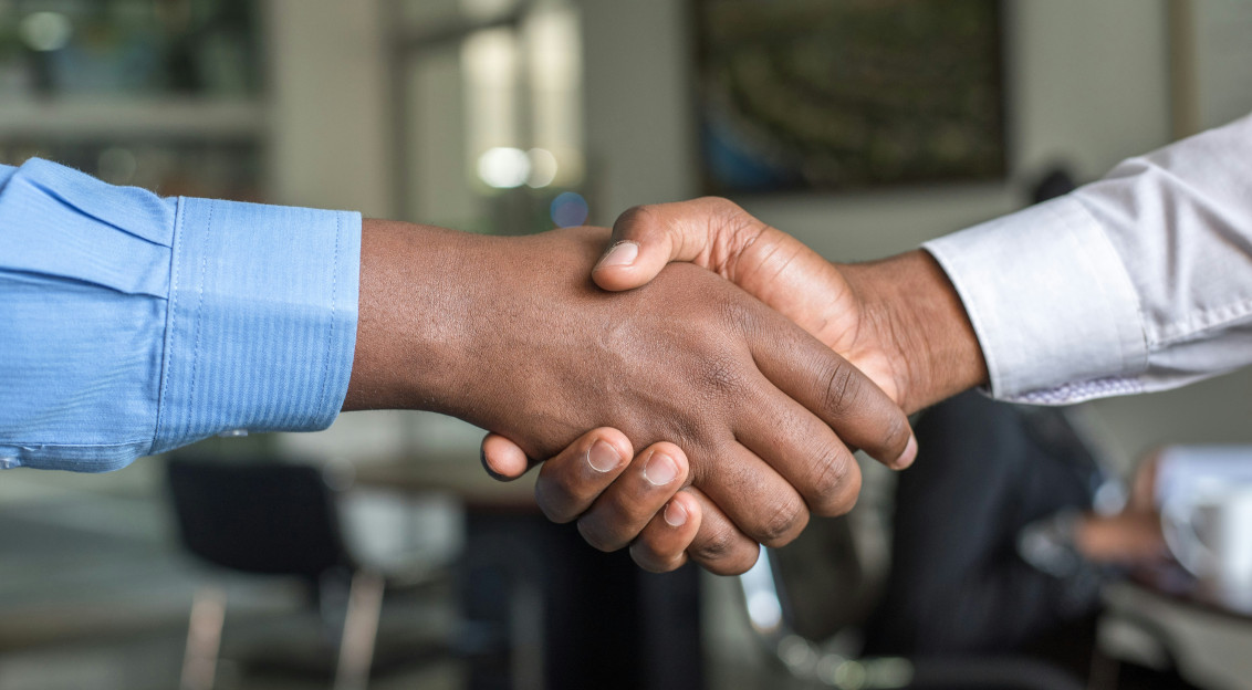 Two business professionals shaking hands during a meeting, representing networking, partnership building and international business collaboration in the textile and fashion industry.