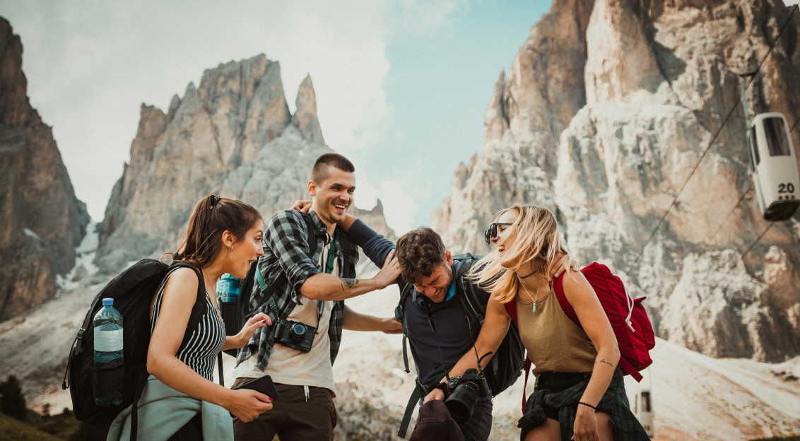 The picture presents a group of hikers laughing together in a rocky mountain setting.