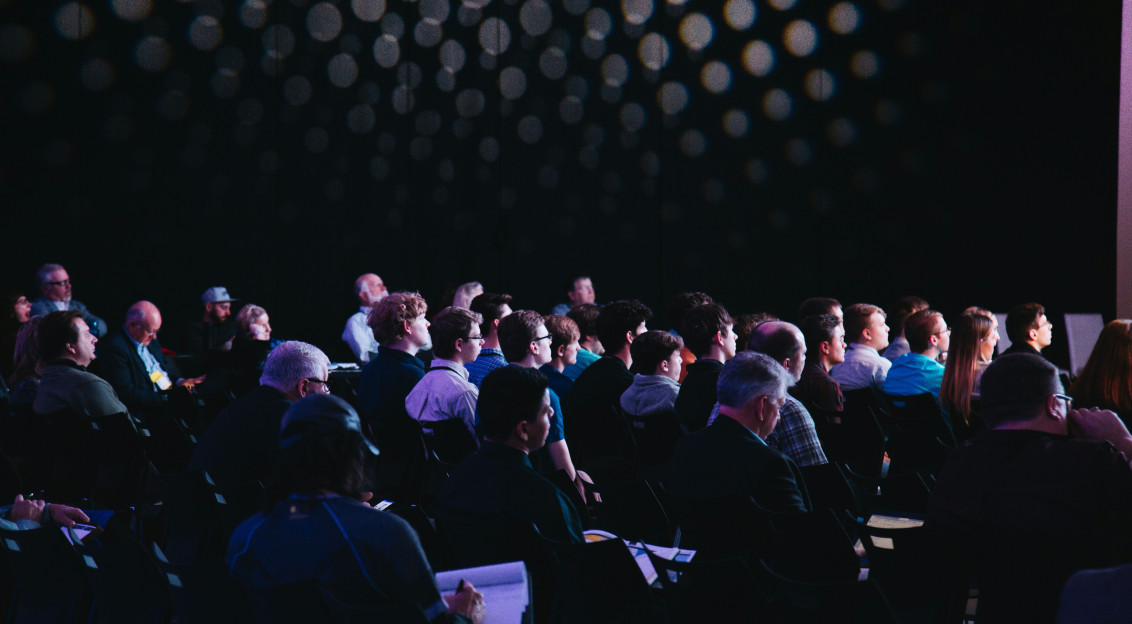 The picture presenting people during the conference looking on the stage.