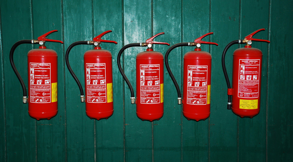 A photo presents fire extinguishers mounted on a green wall.