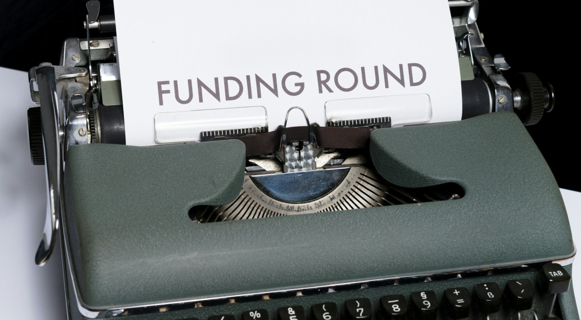Green and white braille typewriter with paper saying ‘Funding round’. 