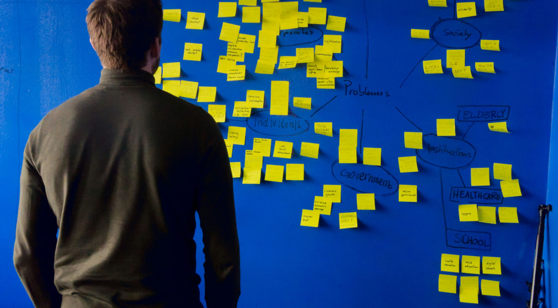 A photo presents a person reviewing notes on a planning board.
