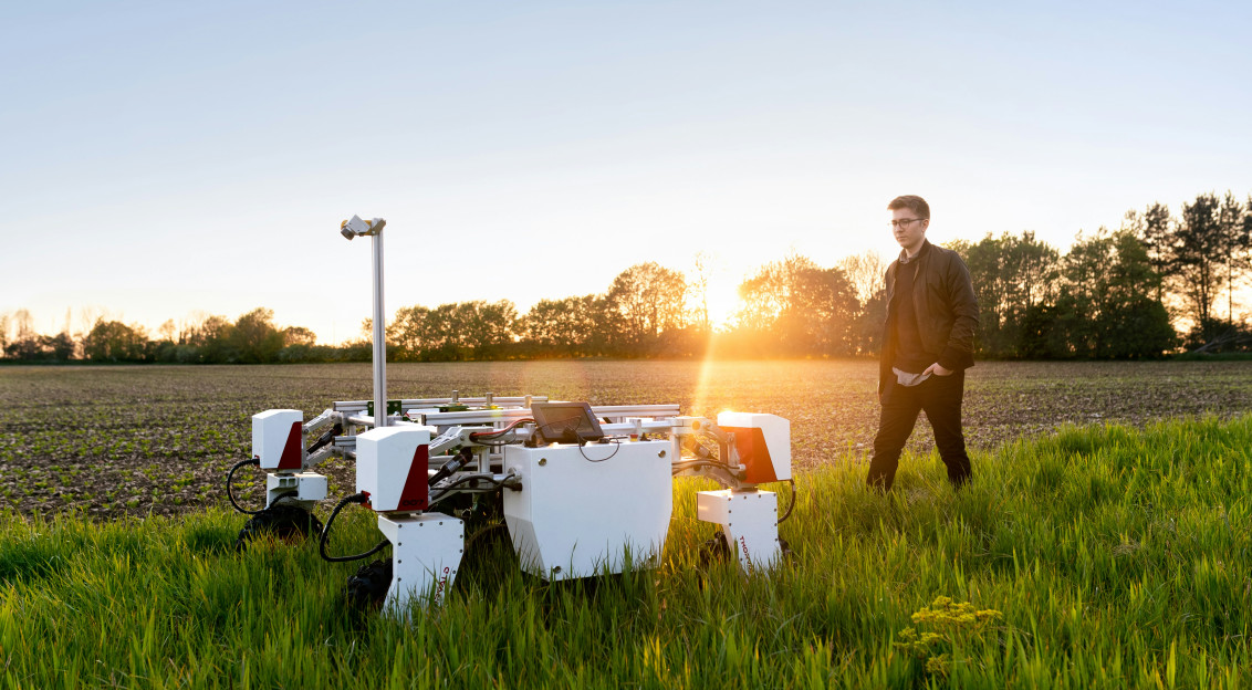 A photo presents a person inspecting agricultural technology in a field.
