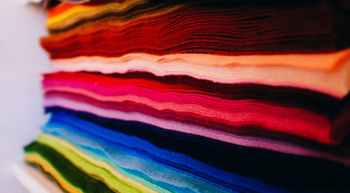 Stack of colourful textile fabrics in red, pink, orange, blue, green and neutral tones