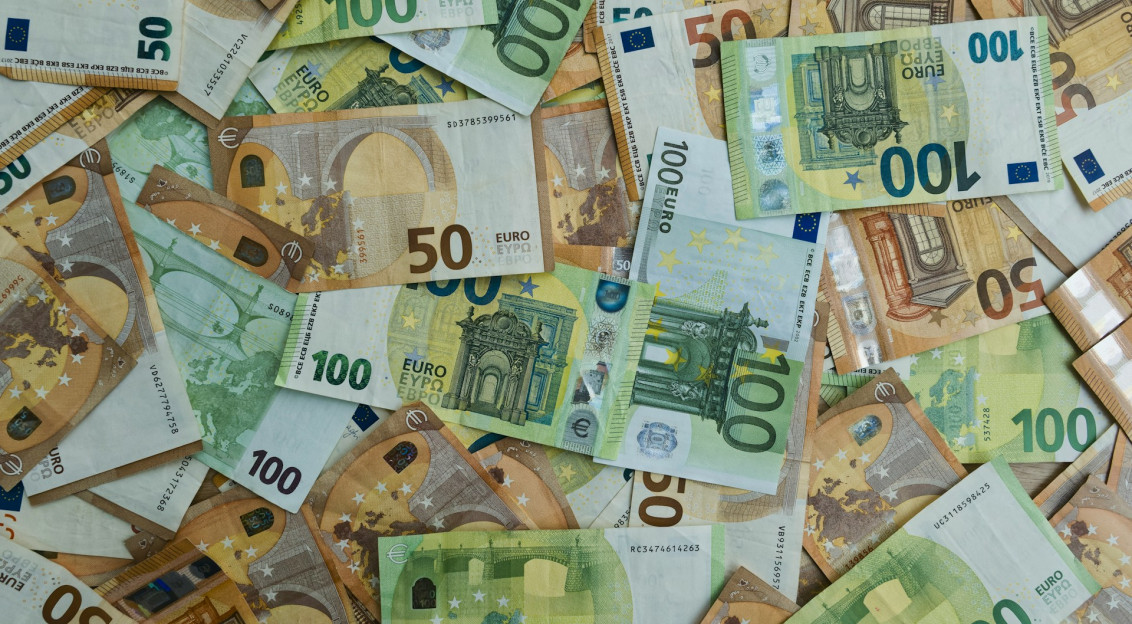 The photo presents a collection of €50 and €100 euro banknotes.