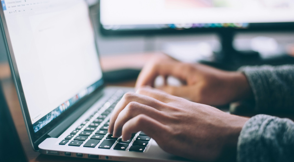 The photo presents a person typing on a laptop.