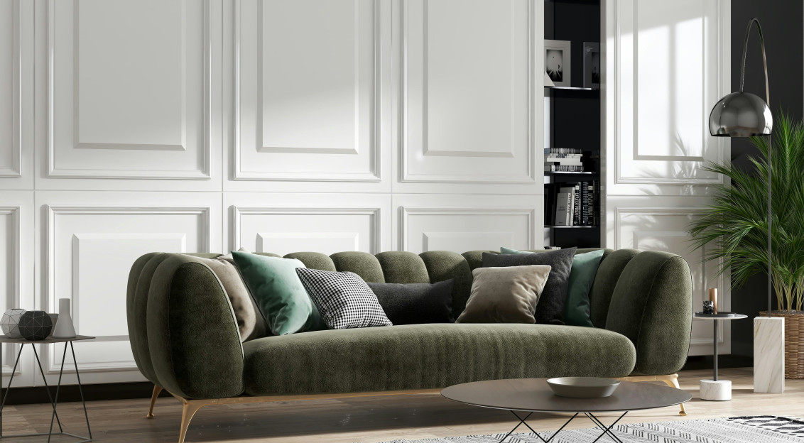 Modern living room with a green upholstered sofa, decorative cushions, a patterned rug and contemporary interior accessories.