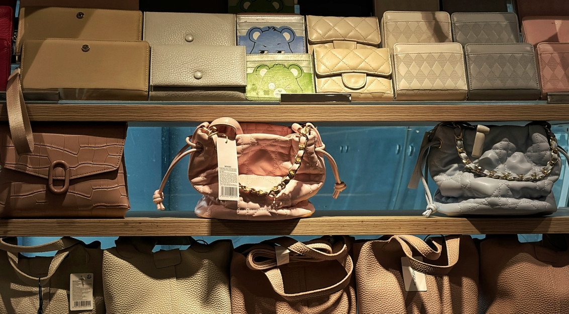 Handbags, wallets and fashion accessories displayed on shelves in a retail setting.
