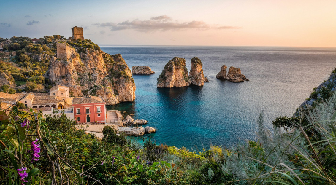 The photo presents a rocky coastline with clear blue sea.
