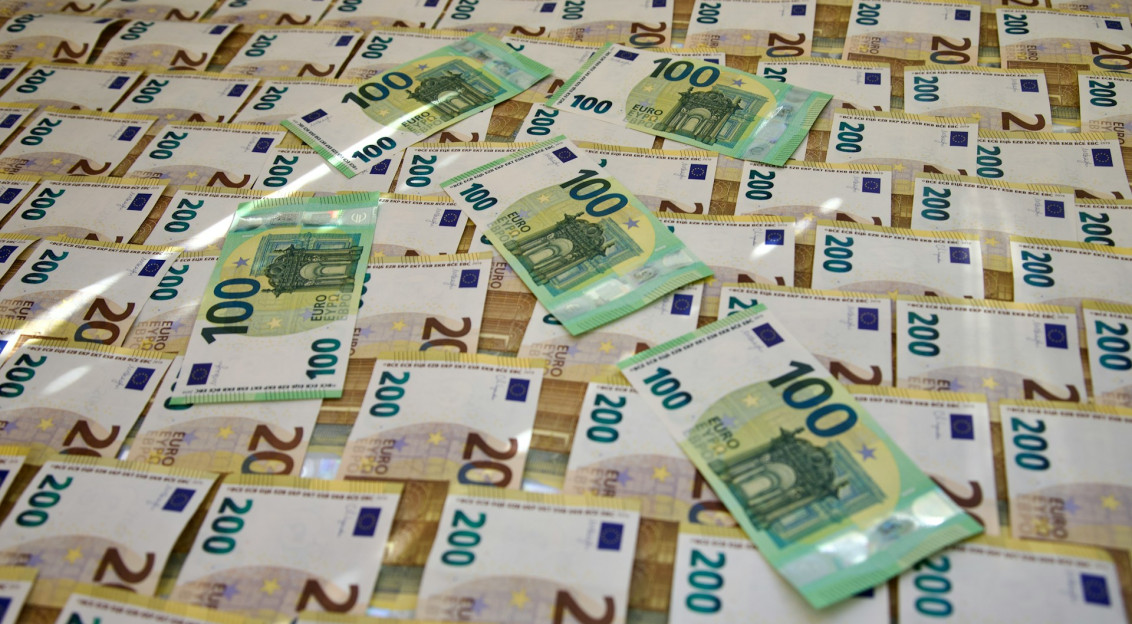 The photo presents stacks of €100 and €200 euro banknotes.