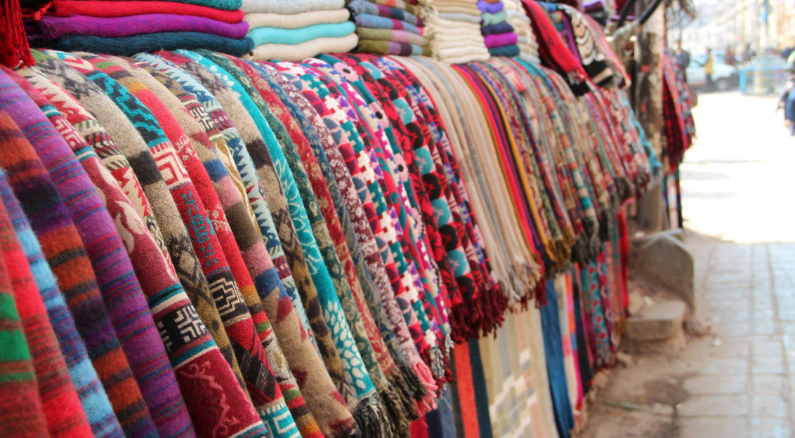 Colourful textiles and patterned fabrics displayed at a fashion market.