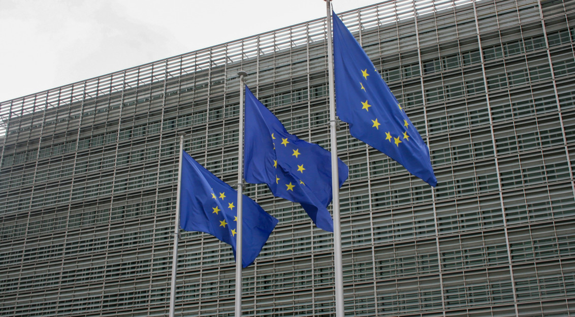 Three European flags flying in front of a building. 