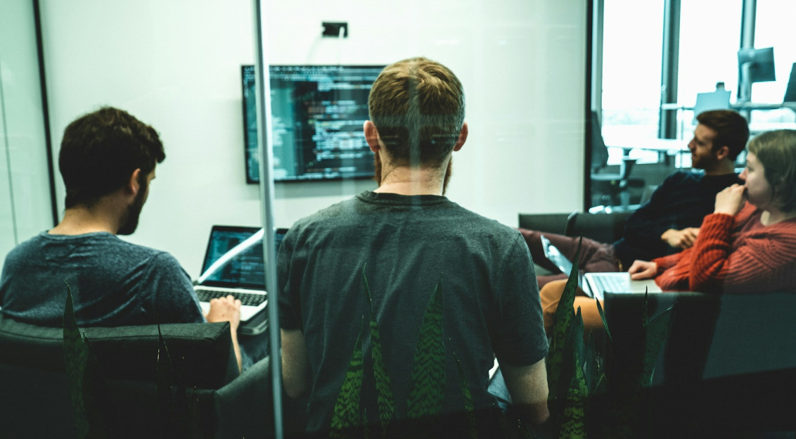 The photo presents a team working on computers.