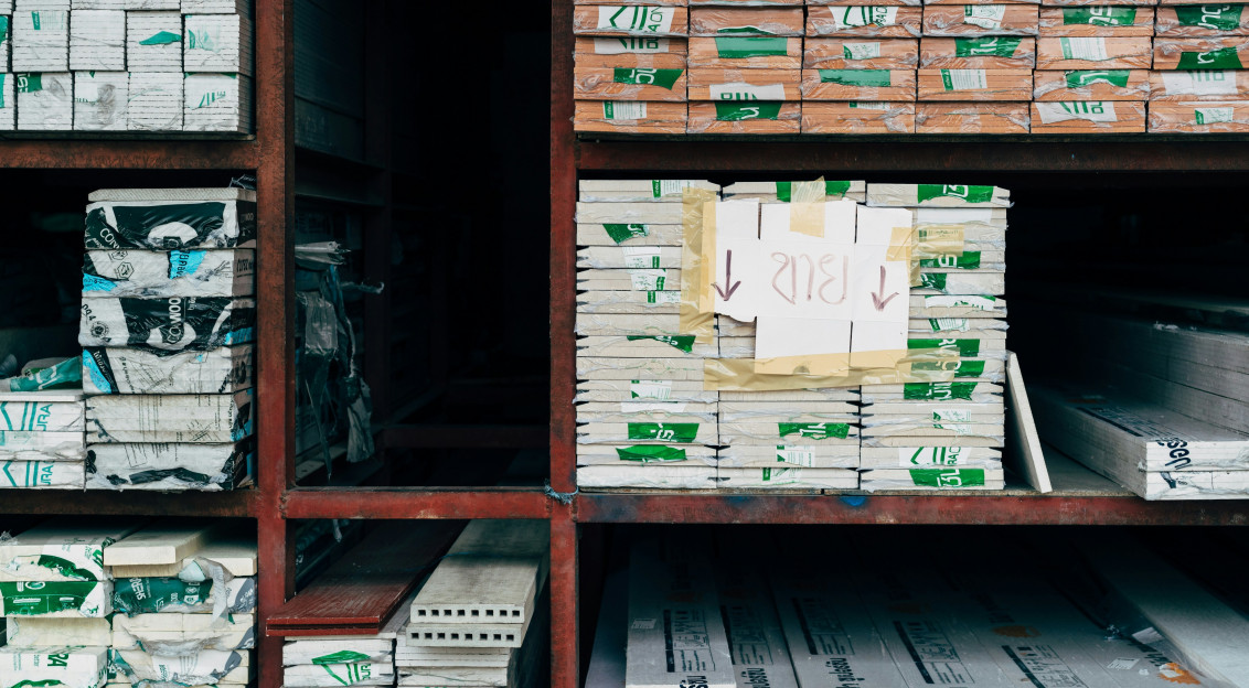 The picture shows stacks of construction and insulation materials neatly stored on industrial warehouse shelving.