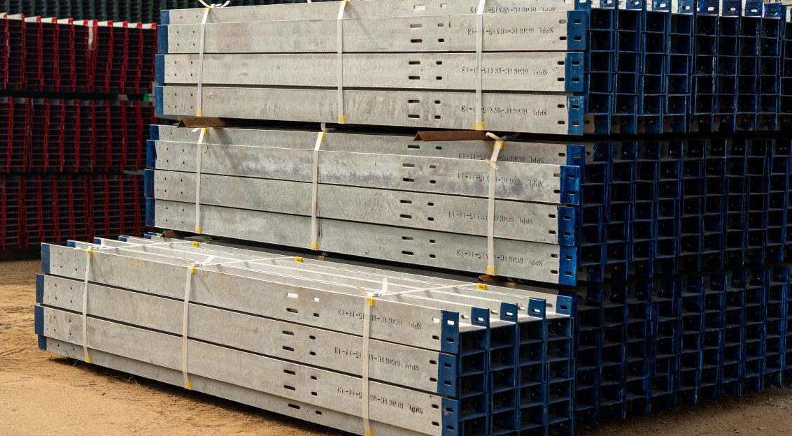 The picture describes stacks of prefabricated steel components stored in an industrial yard for use in construction projects.
