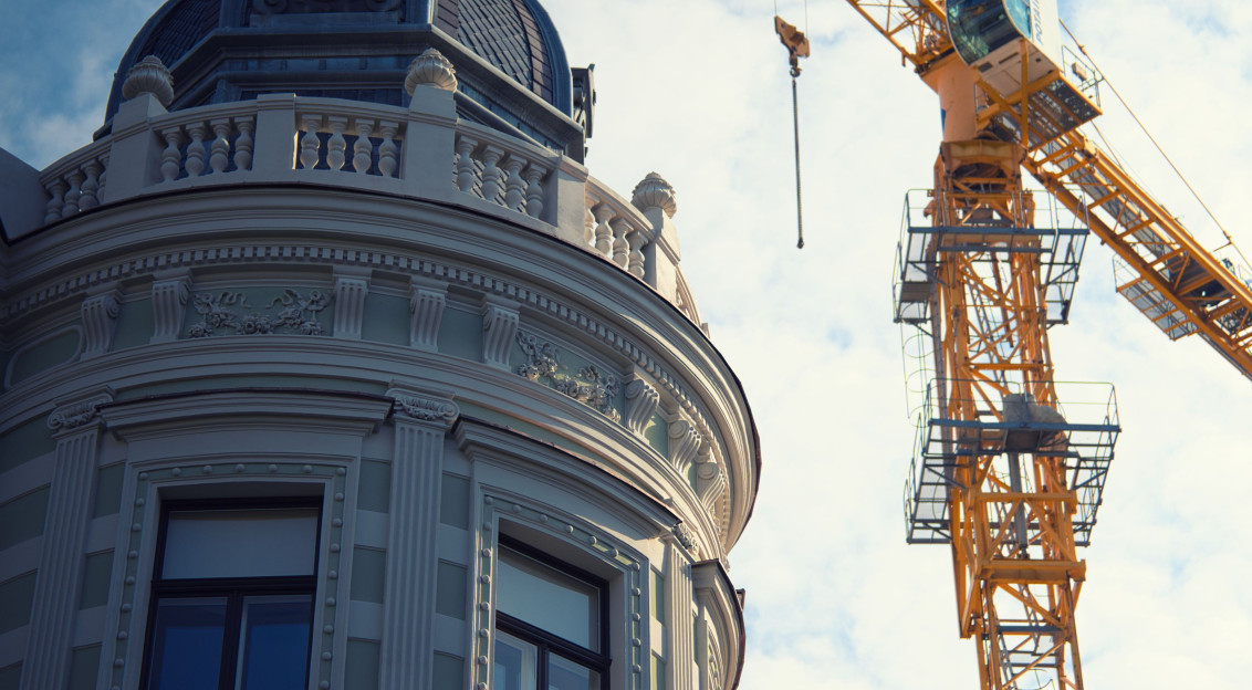 The picture describes the restoration or redevelopment of a historic urban building alongside modern construction activity.