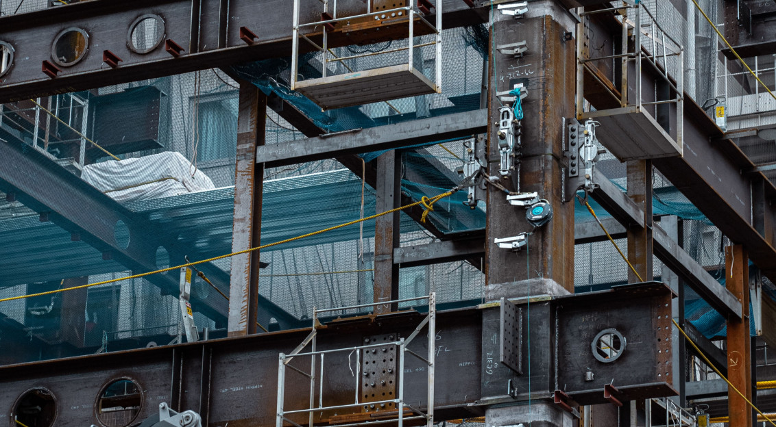 The picture describes a steel-frame building under construction in an urban environment.