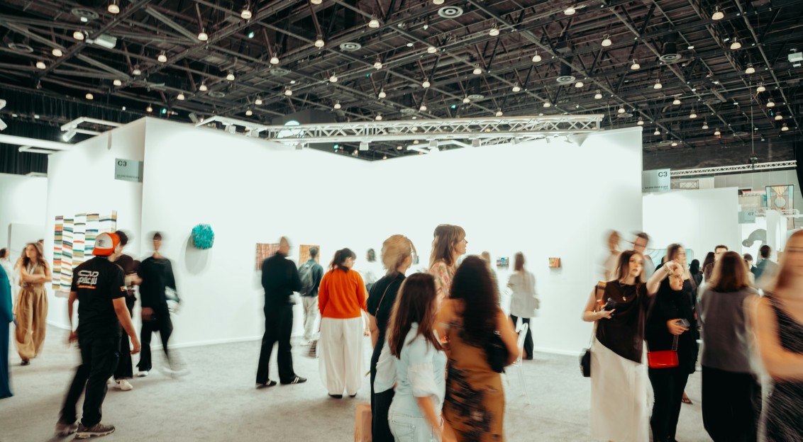 Visitors walking through a large exhibition hall with illuminated booths and displays during a professional trade fair.