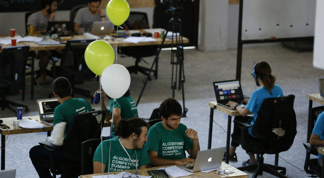 The photo presents participants working at a programming competition or hackathon.