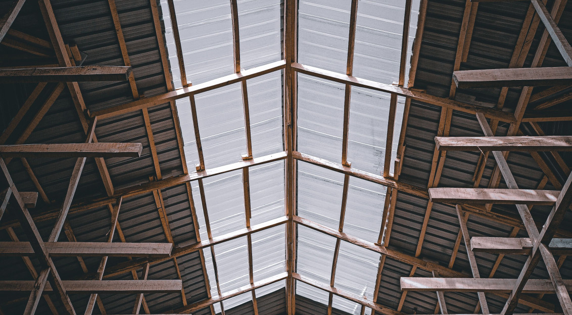 This picture shows the interior roof structure of a large industrial or agricultural building, photographed looking upward.