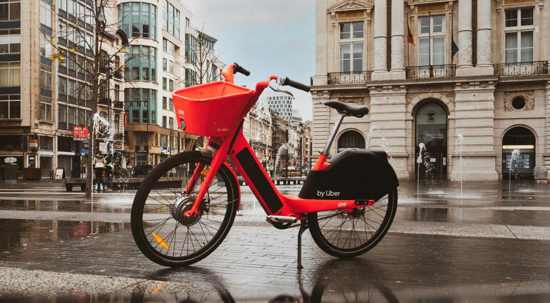 An illustrative photo of a red and black bicycle on road in the city