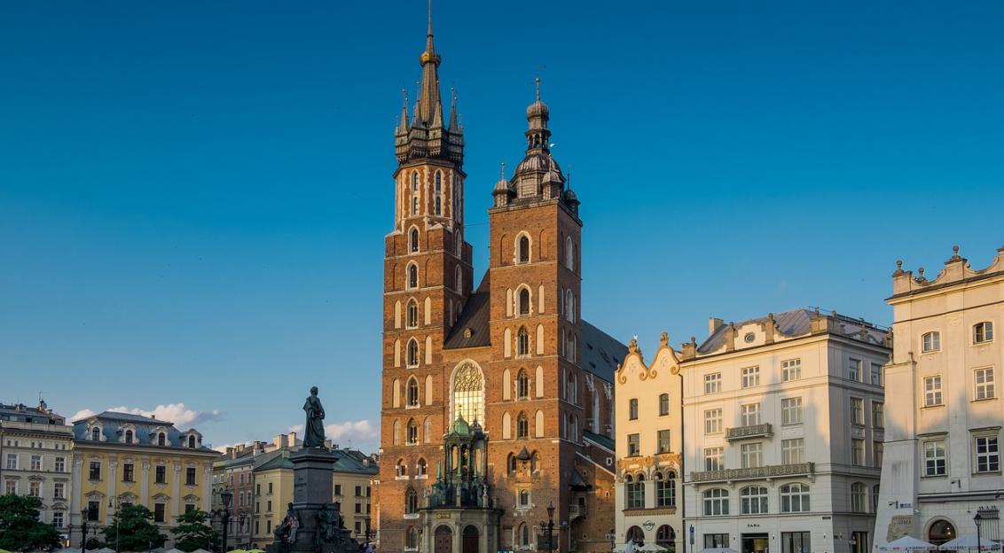 An illustrative photo of a brown church on the square with many people in Poland