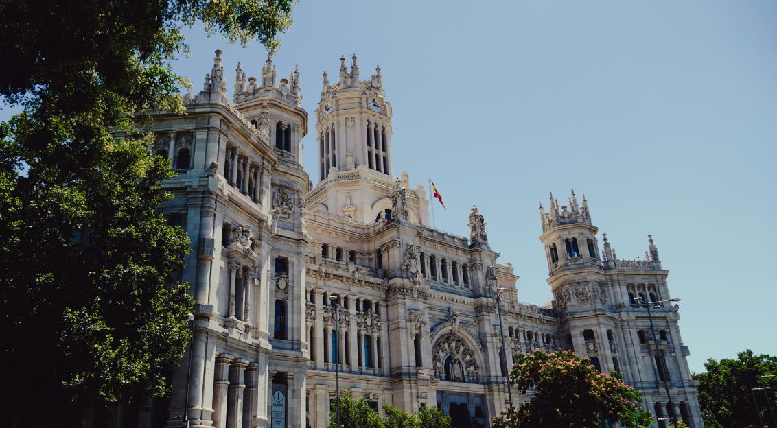 An illustrative photo of a large white building with a clock tower on top of it in Madrid.