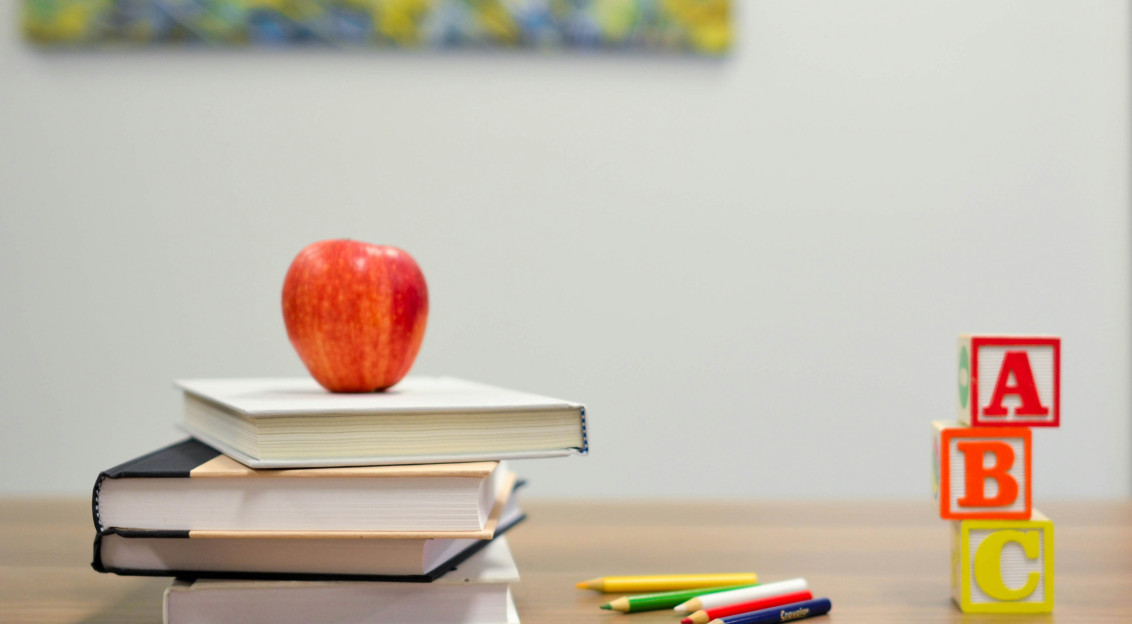 An illustrative photo of a red apple on four books