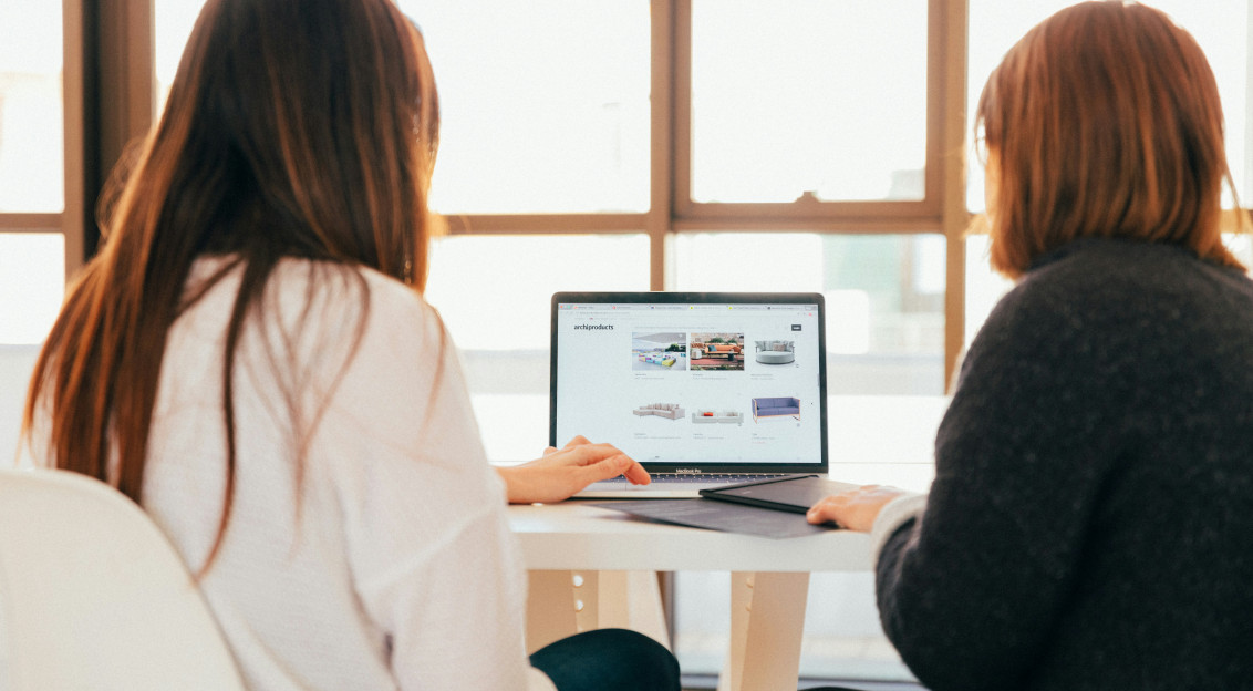 Photo by Unsplash An illustrative photo of two women talking while looking at laptop computer