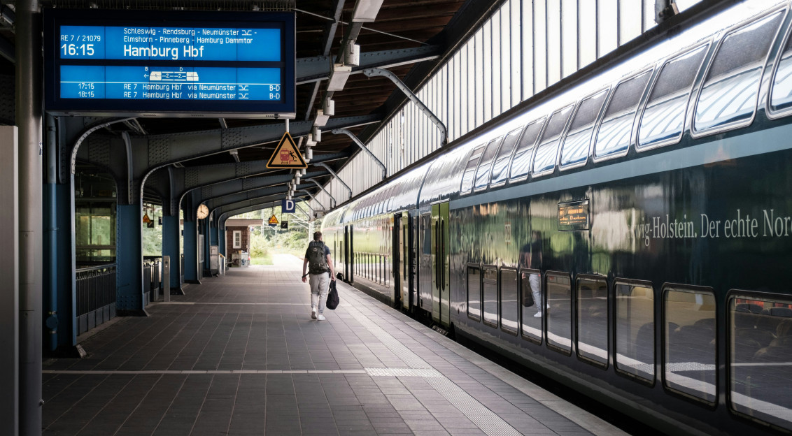 An illustrative photo of a man walking near a train on a train station 