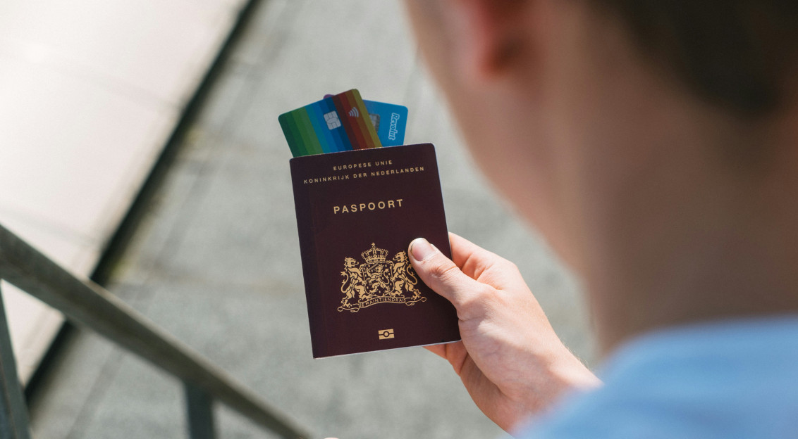 Photo by Unsplash An illustrative photo of a person holding a passport with banking cards in it