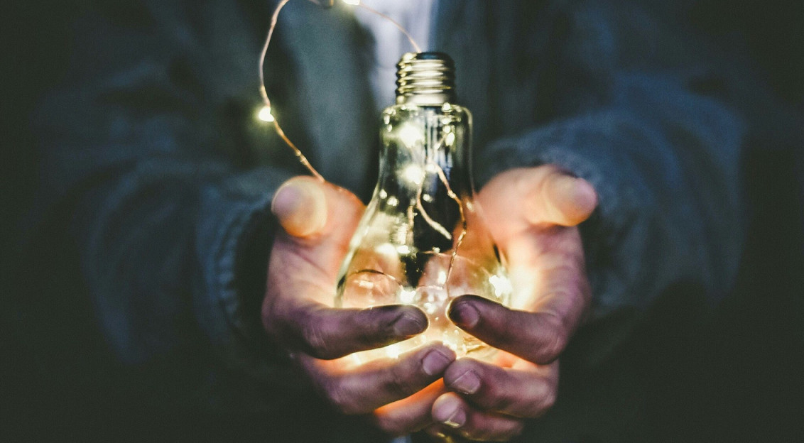 An illustrative photo of a man holding incandescent bulb