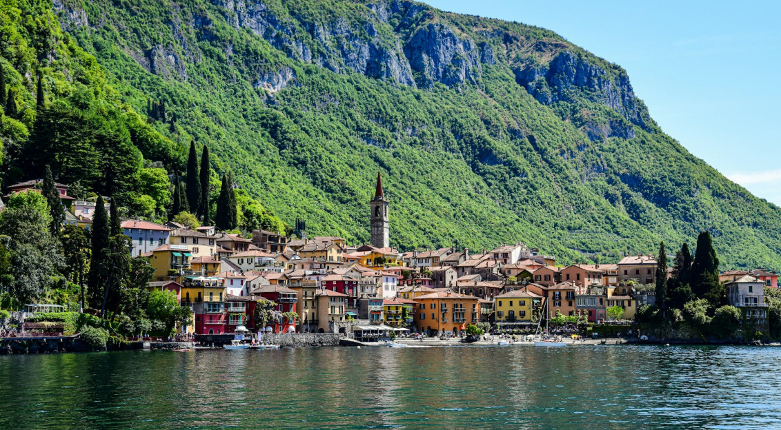 An illustrative photo of a town by a body of water with mountain in the background
