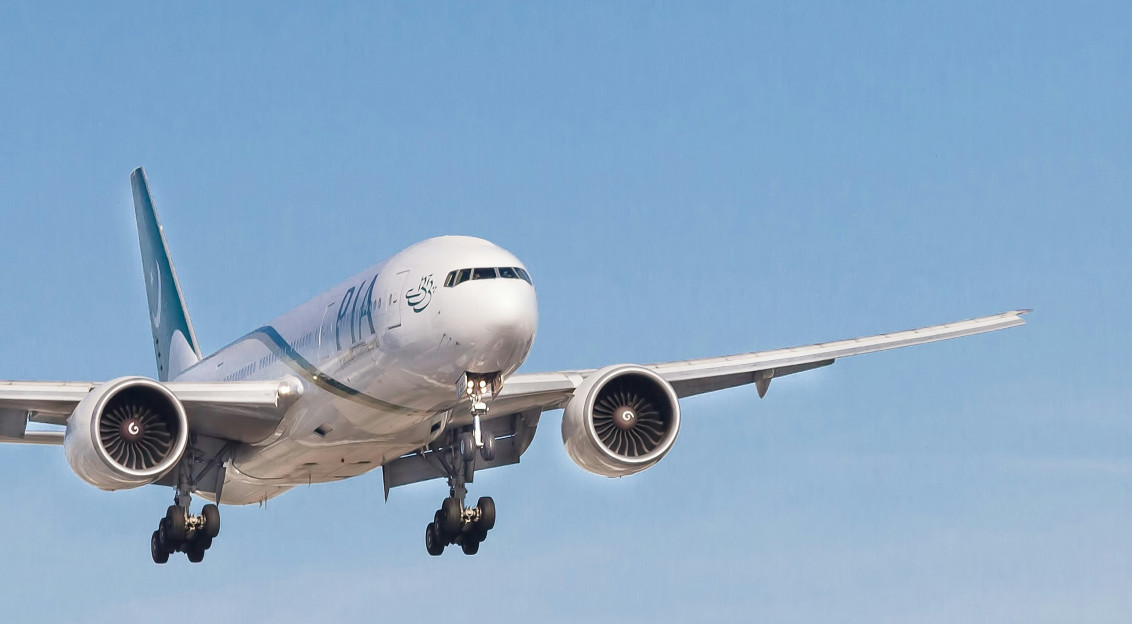 An illustrative photo of a white airplane in the blue sky