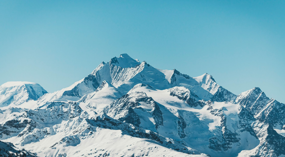 An illustrative photo of a snow covered mountain under blue sky