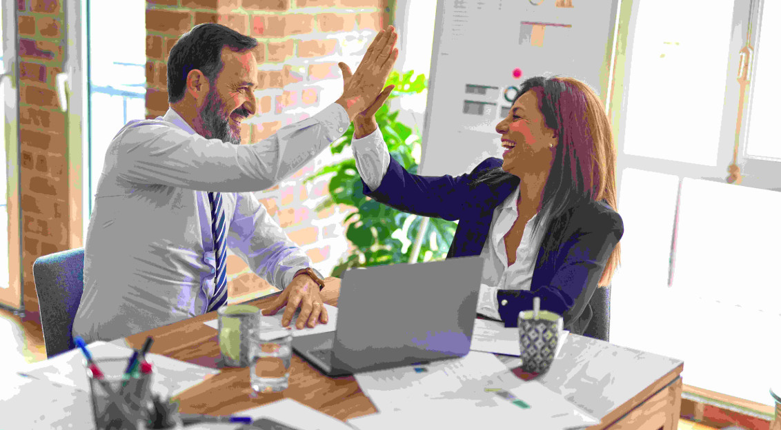 An illustrative photo of two business workers smiling while working.