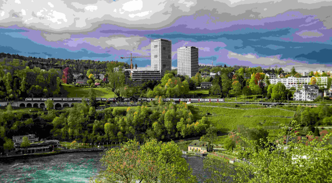 Image by Unsplash An illustrative photo of a river running through a green forest with high-rise buildings in the background.