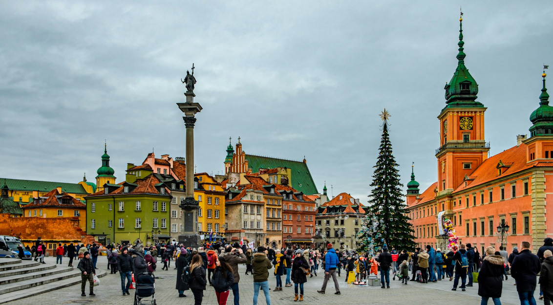 An illustrative photo of people walking on a square with a Christmas tree.