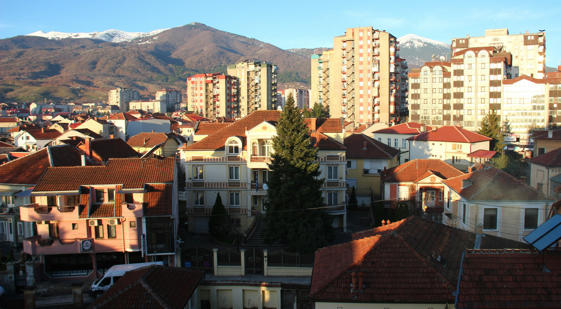 An illustrative photo of city buildings with mountains in the background.