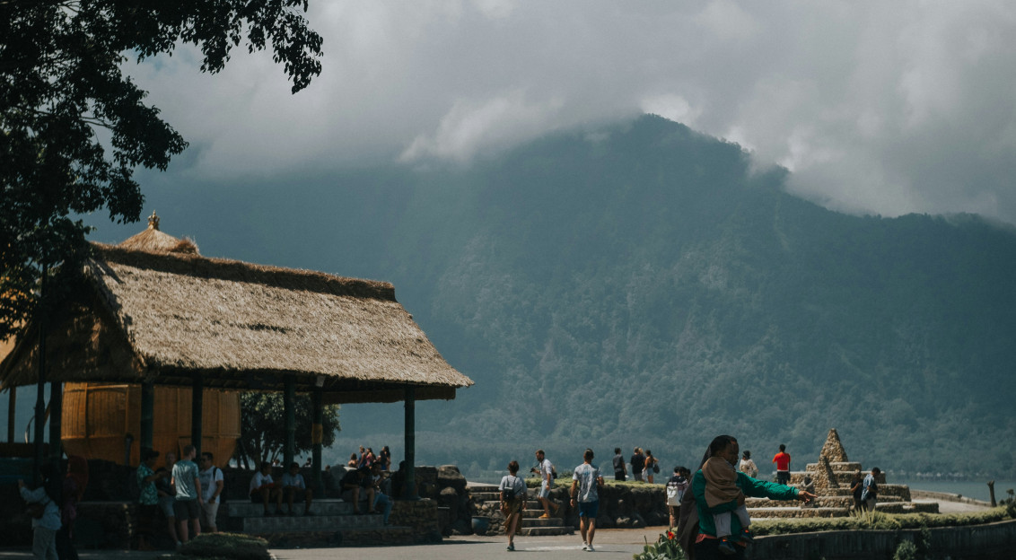 An illustrative photo of people walking near a mountain during a foggy weather.
