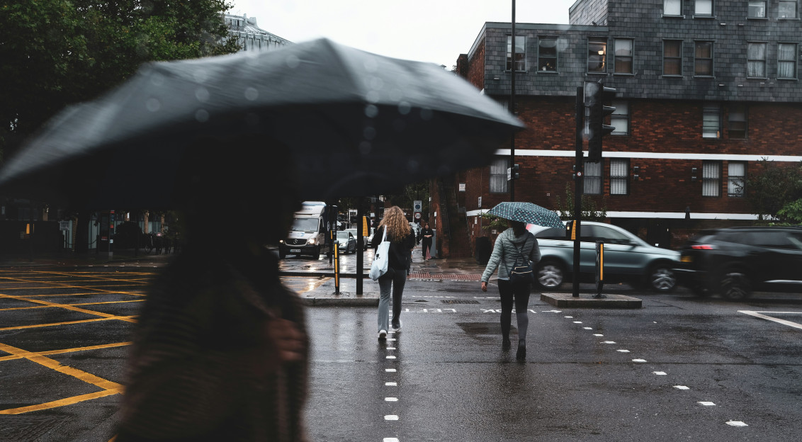 Image by Unsplash An illustrative photo of a woman walking down a street holding an umbrella.