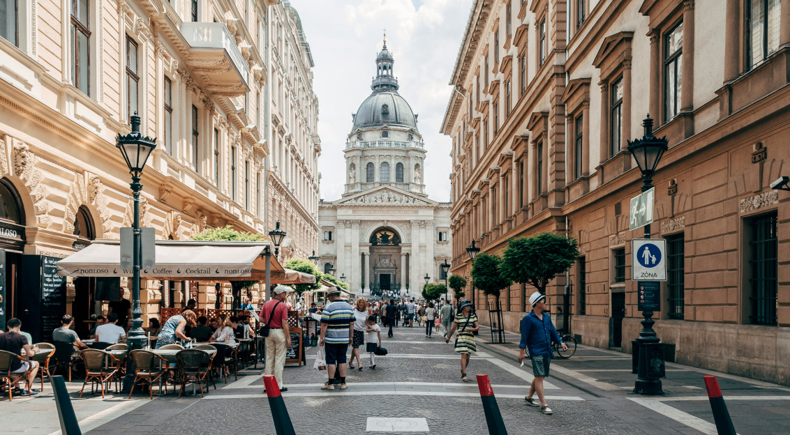 An illustrative photo of people walking on a street near brown concrete building.