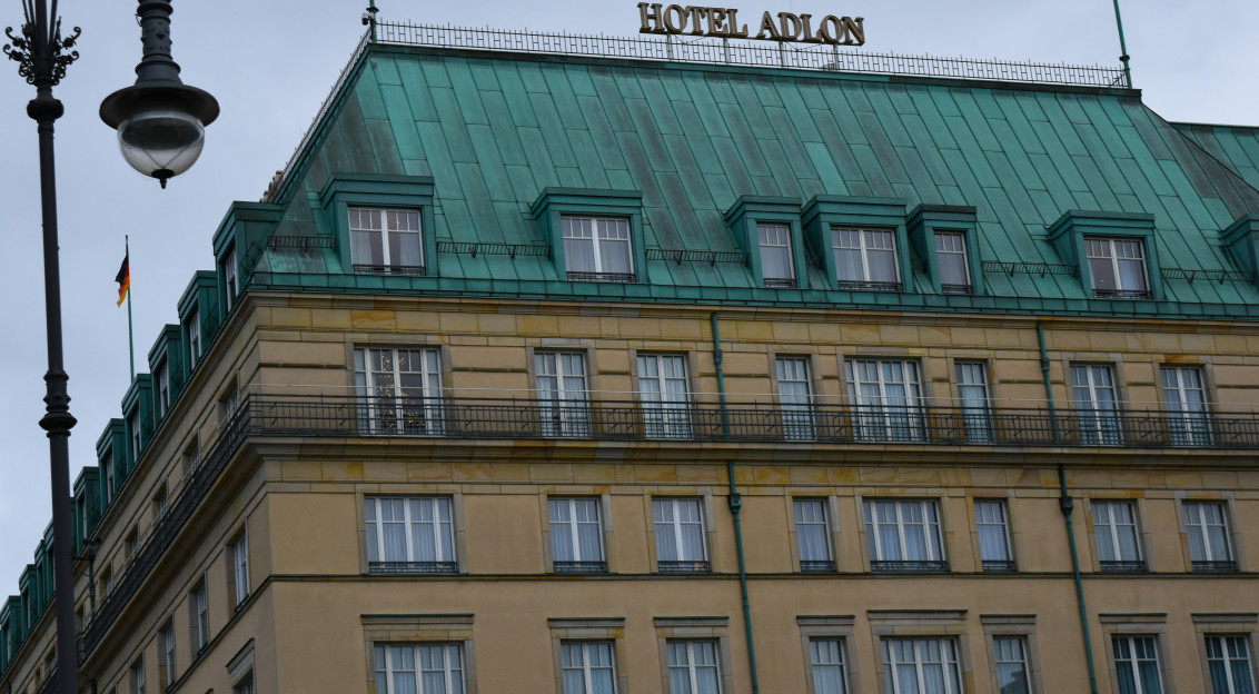 An illustrative photo of a tall building with a green roof and a street light.