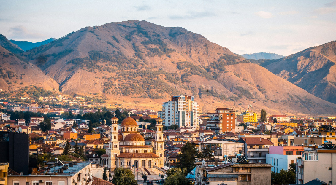 An illustrative photo of a city with mountains in the background.