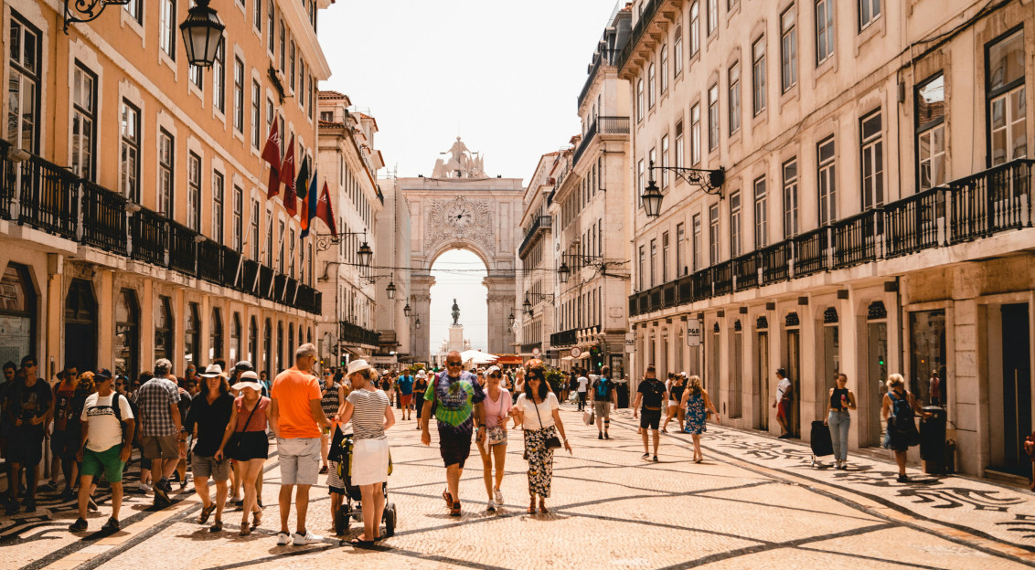 Photo by Unsplash An illustrative photo of people walking on a street near beige buildings.