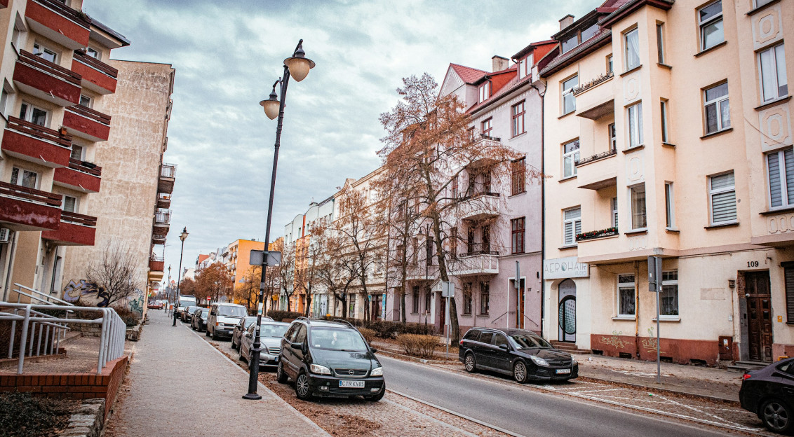 Photo by Unsplash An illustrative photo of a street lined with parked cars next to tall buildings