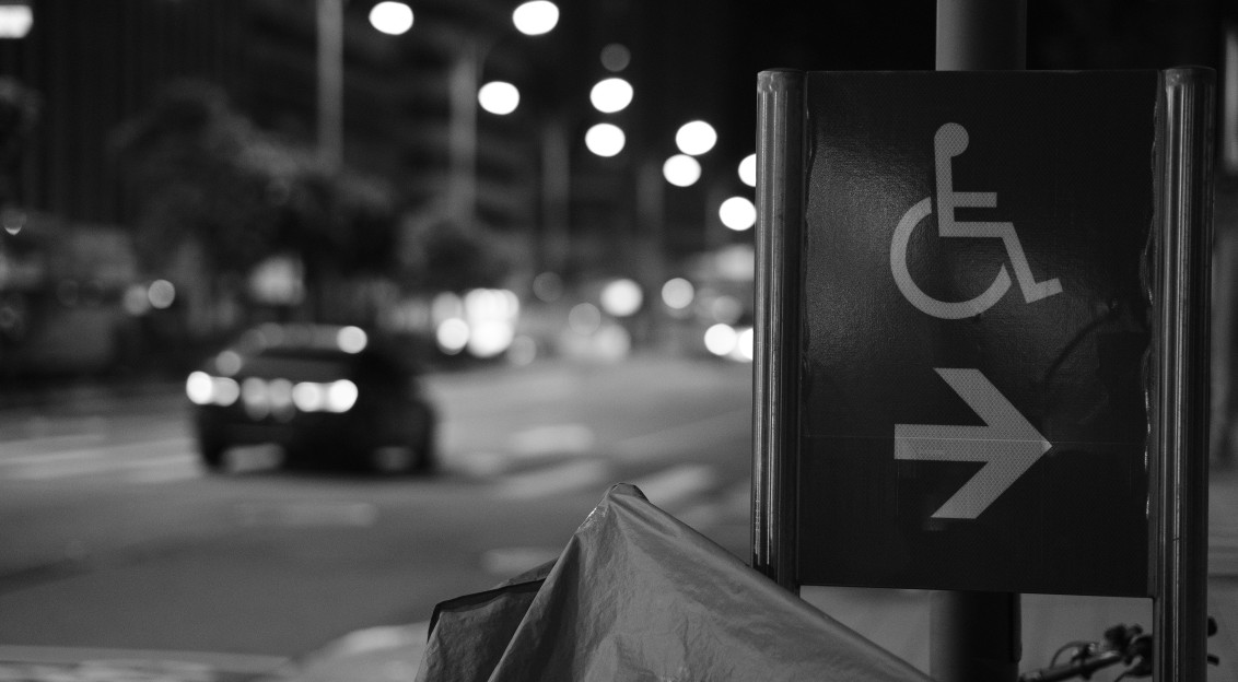 An illustrative photo of a handicapped parking sign on a city street.
