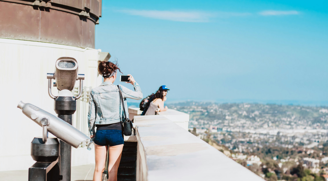 An illustrative photo of a woman standing on a terrace facing city.