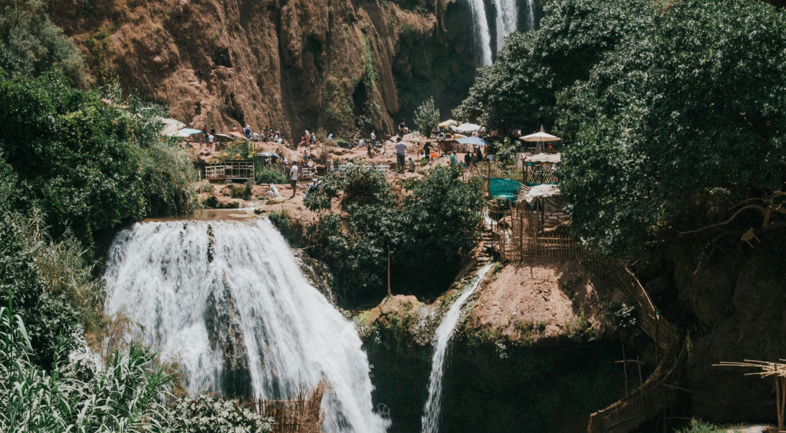 An illustrative photo of people on a hill beside waterfalls.